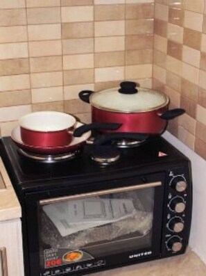 A kitchen with a black stove, two pots, and a microwave. - Amazing Studio 9 minutes walk from Center (Thessaloniki)