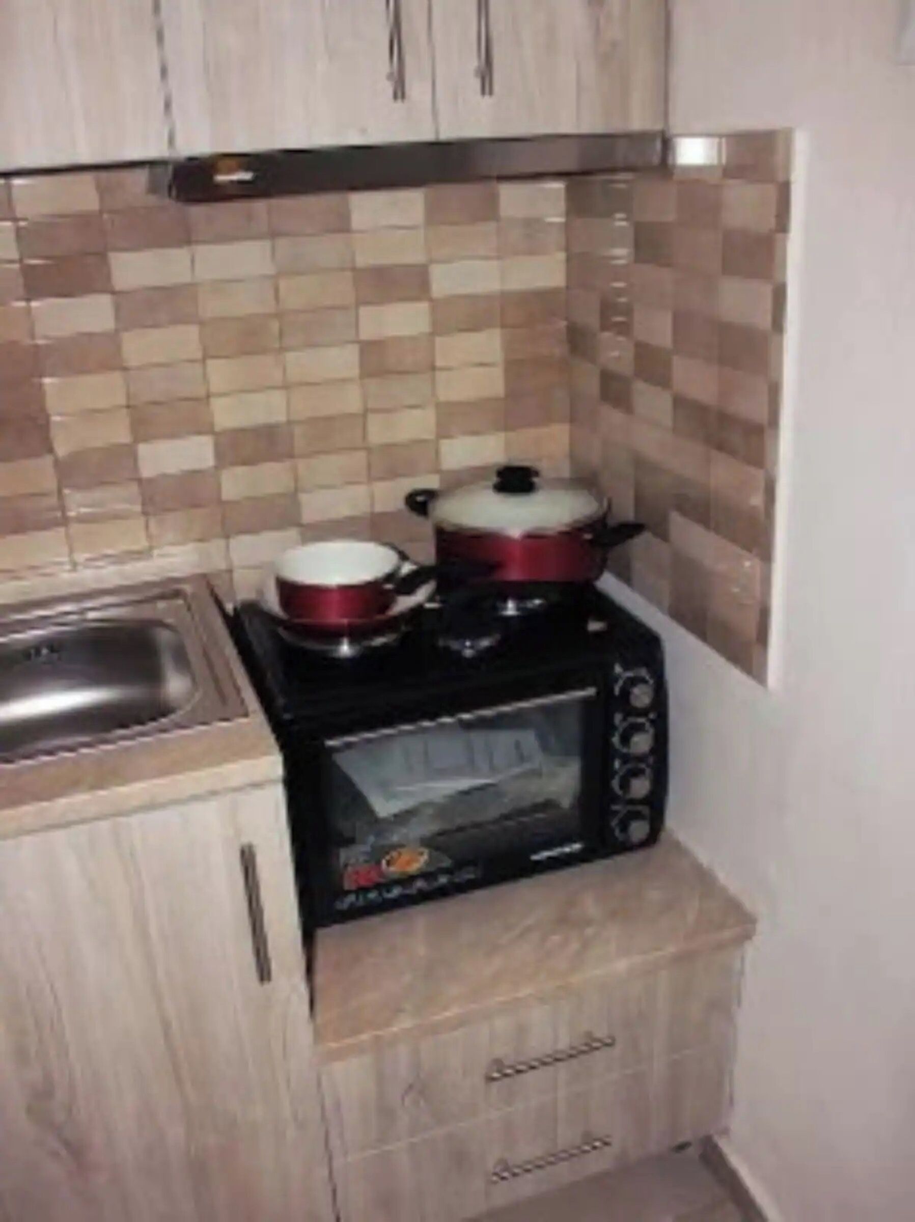 A compact kitchen with a microwave, a small oven, and a sink.