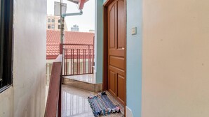 Una escalera que lleva a un balcón con un tejado de tejas rojas al fondo.