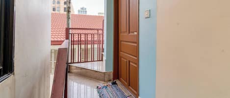 A staircase leading to a balcony with a red-tiled roof in the background.