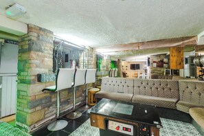 A room with a sofa, a coffee table, a TV, and a stone wall.