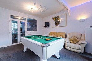 Een pooltafel in een kamer met een bank en een televisie.