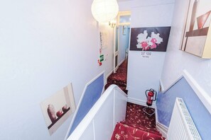 A staircase with a red carpet, a 'QUIET PLEASE' sign, and a fire extinguisher.