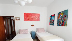 A bedroom with two beds, a red abstract painting, and two colorful paintings on the wall. - Modern Apartment Near Senigallia's Velvet Beach (Senigallia)