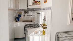 A compact kitchen with white cabinets, a gas stove, a sink, and a spice rack. - Modern Apartment Near Senigallia's Velvet Beach (Senigallia)