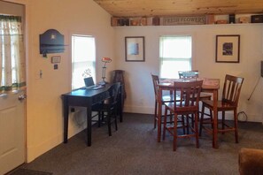A room with a desk, two chairs, a table, and a window with blinds. - Charming Home on Main Street in Deadwood! (Deadwood)