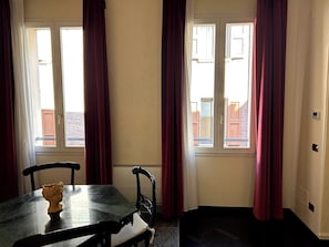 Um quarto com uma mesa de jantar, duas cadeiras e uma janela com cortinas.
