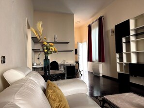 Ein modernes Wohnzimmer mit einer Couch, einem Esstisch und einer Küchenzeile im Hintergrund.