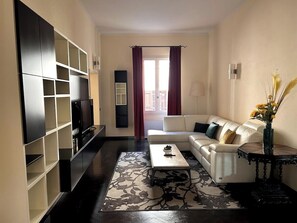 Ein Wohnzimmer mit einer Couch, einem Couchtisch und einem Fernseher auf einem Schrank.