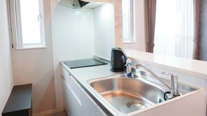 A modern kitchen with a stainless steel sink, a kettle, and a small cabinet. - HOTEL MELNA HAKATA (Fukuoka City)