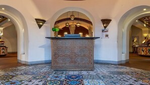 A lobby with a patterned floor, a reception desk, and a decorative ceiling.