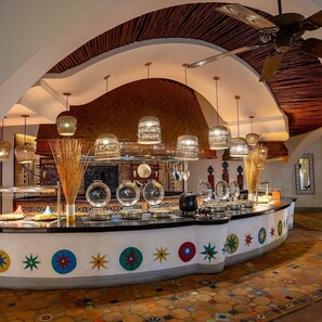 A buffet area with a variety of dishes, a ceiling fan, and decorative lighting.