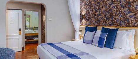 Habitación de hotel con una cama grande, baño con espejo y pared con diseño.