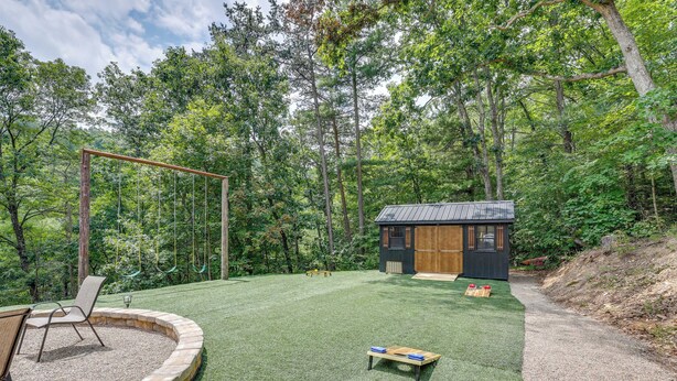 A backyard with a swing set, a small wooden playhouse, and a fire pit area. - Swings, Fire Pit + Views: Shirleysburg Cabin! (Shirleysburg)