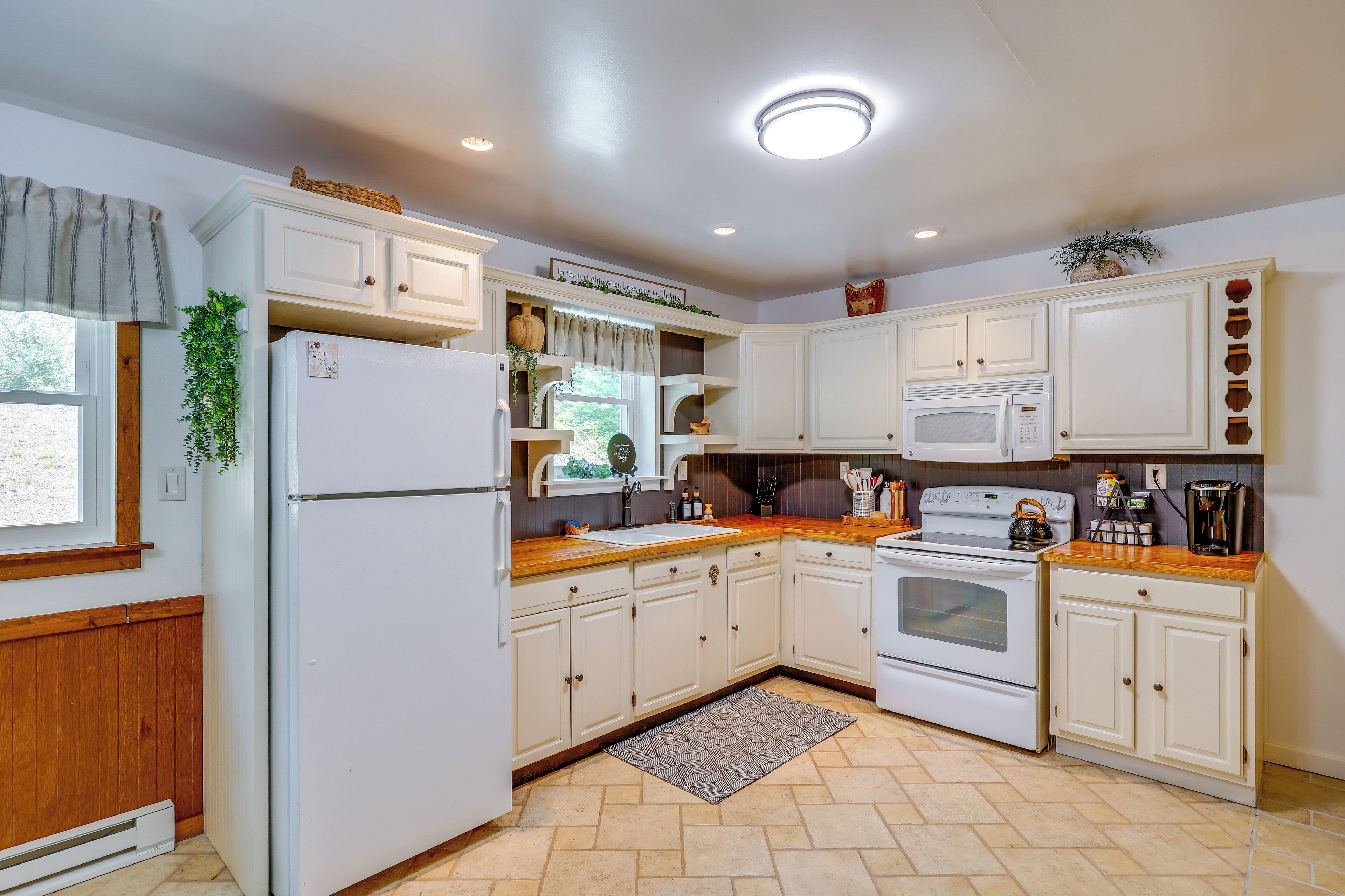 A kitchen with white cabinets, a built-in oven, a microwave, and a refrigerator.