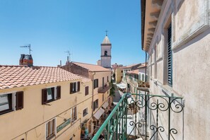 Una calle estrecha flanqueada por edificios, una torre de campanas y un cielo azul despejado.