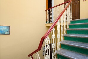 Un escalier avec des rampes blanches richement décorées et des marches vertes.