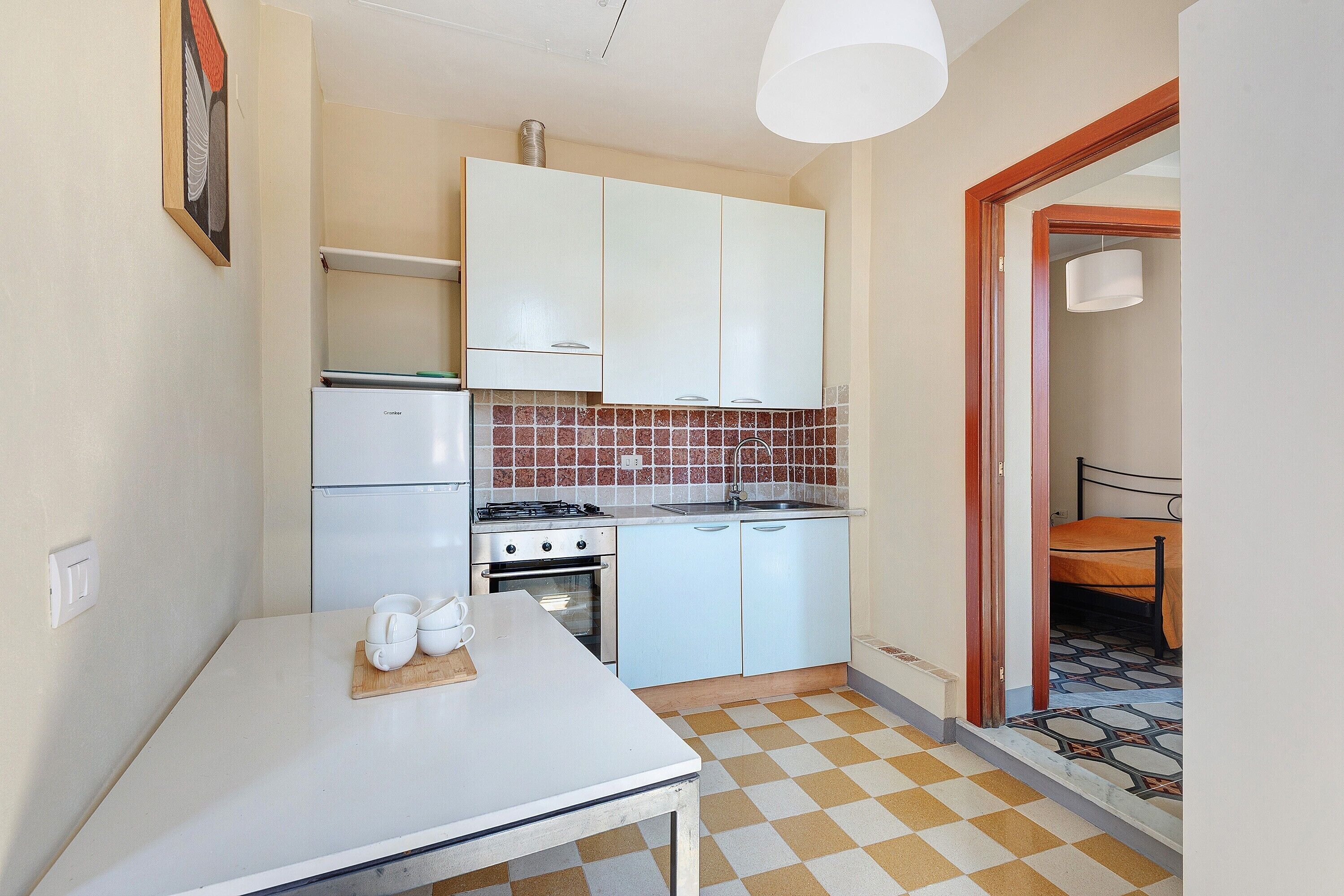Une cuisine de taille réduite, équipée d’un réfrigérateur, d’une cuisinière et d’un évier.