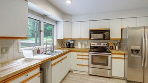 Uma cozinha moderna com eletrodomésticos de aço inoxidável, bancadas de madeira e uma janela com vista para o exterior.