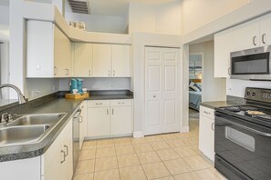 A modern kitchen with white cabinets, a built-in oven, a microwave, and a sink. - 8 Mi to Englewood Beach! Canal-Front Family Haven (Rotonda West)