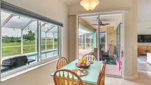 A dining area with a table and chairs, a view of a swimming pool, and a sliding glass door leading to an outdoor patio. - 8 Mi to Englewood Beach! Canal-Front Family Haven (Rotonda West)