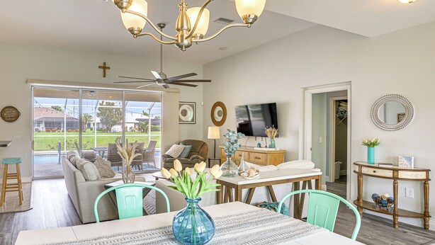 A spacious living area with a dining table, chairs, a sofa, and a television. - 8 Mi to Englewood Beach! Canal-Front Family Haven (Rotonda West)