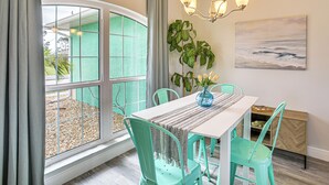 A dining area with a table, chairs, a chandelier, a painting, and a view through a large window. - 8 Mi to Englewood Beach! Canal-Front Family Haven (Rotonda West)