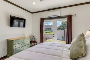 A bedroom with a bed, a dresser, a chair, and a television mounted on the wall. - Close to Lake Chatuge! Modern Hillside Barndo Apt! (Hiawassee)