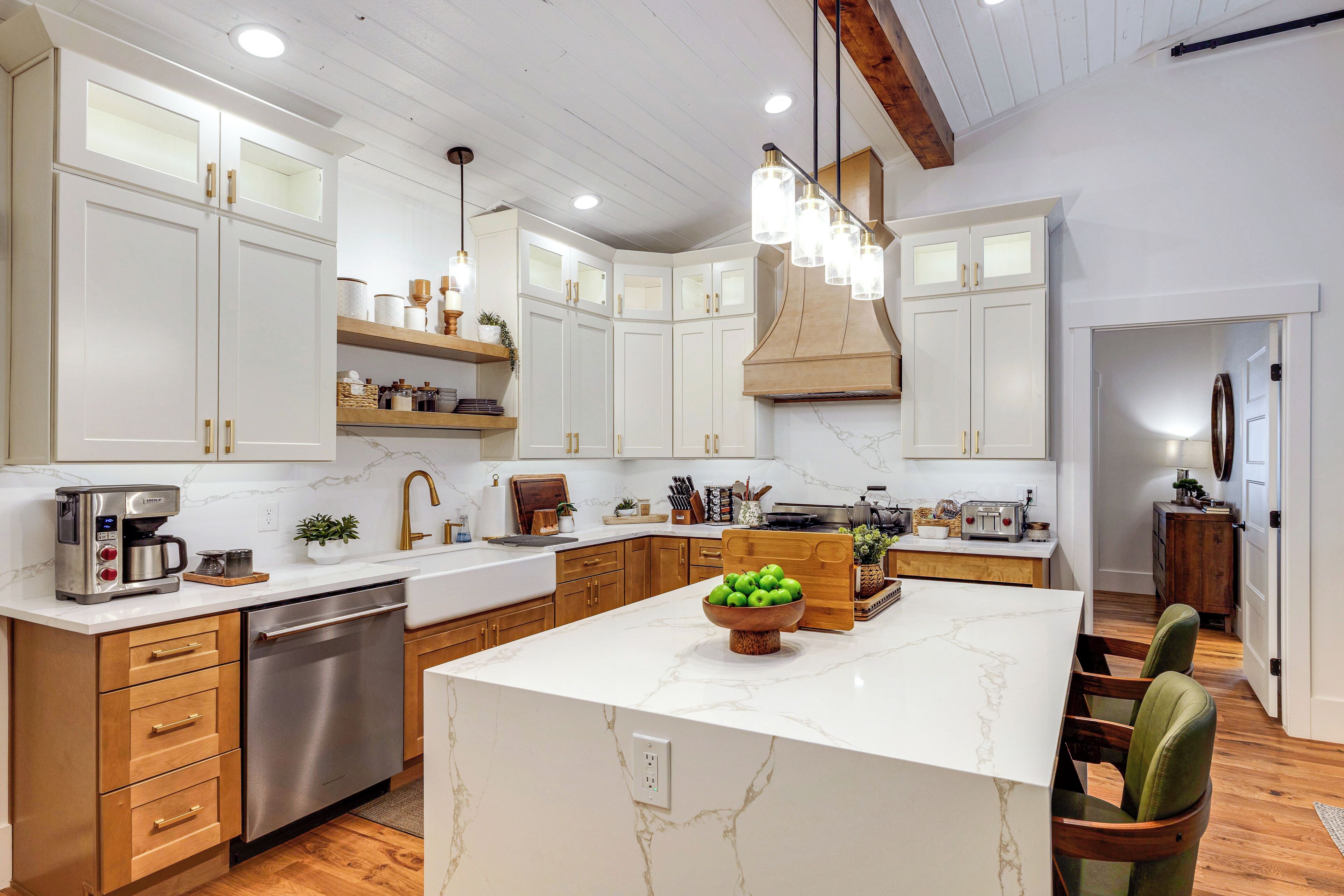 A modern kitchen with white cabinetry, a central island, and a wooden ceiling.