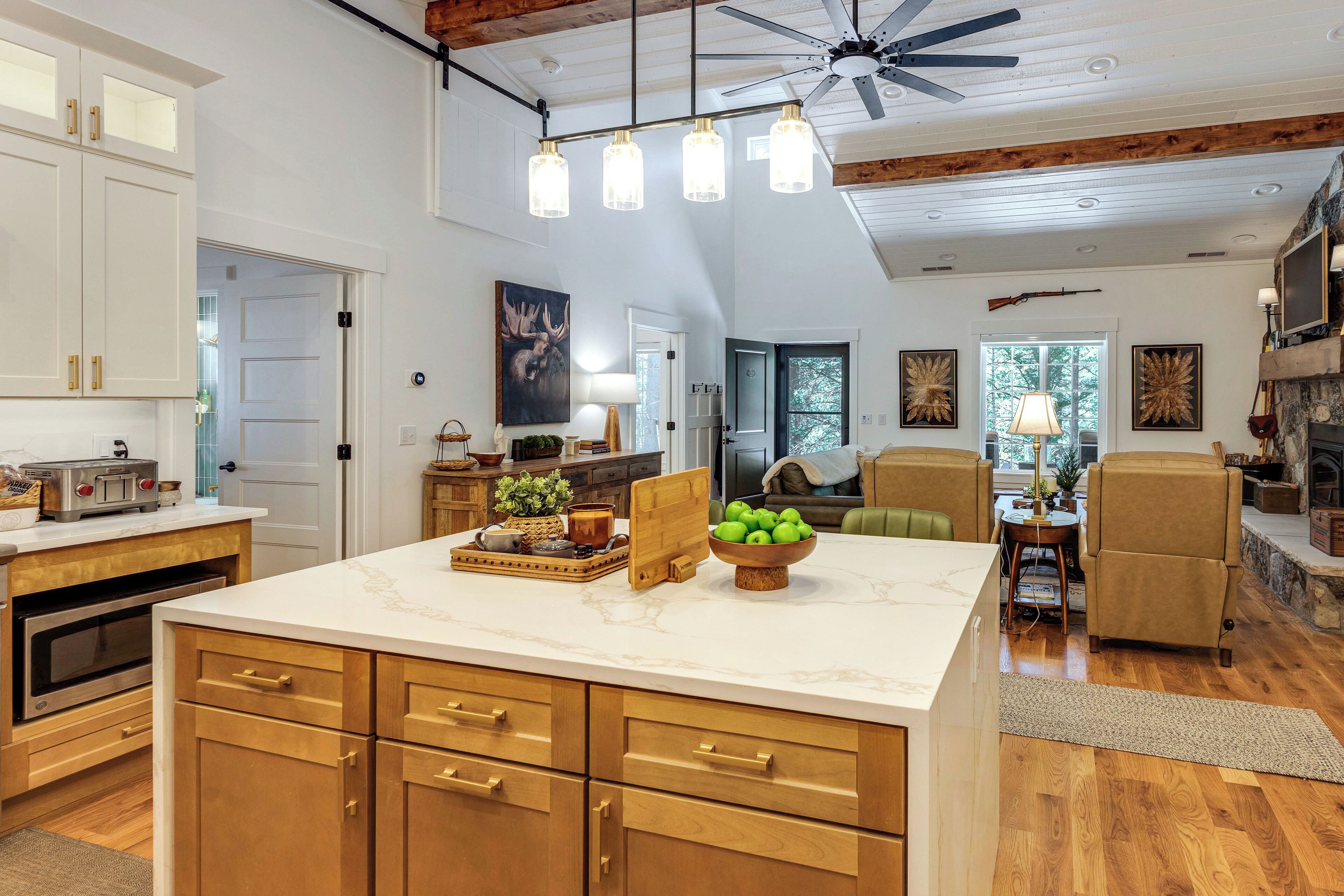 A spacious kitchen with a marble countertop, wooden cabinets, and a ceiling fan.
