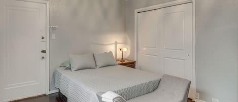 Un dormitorio con una cama, una mesita de noche, una lámpara y dos puertas.