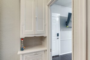 A white door with a keyhole and a handle, a white wall with a textured finish, and a small shelf with a bottle. - Walk Everywhere! Monte Vista Apartment Near Cafes (San Antonio)