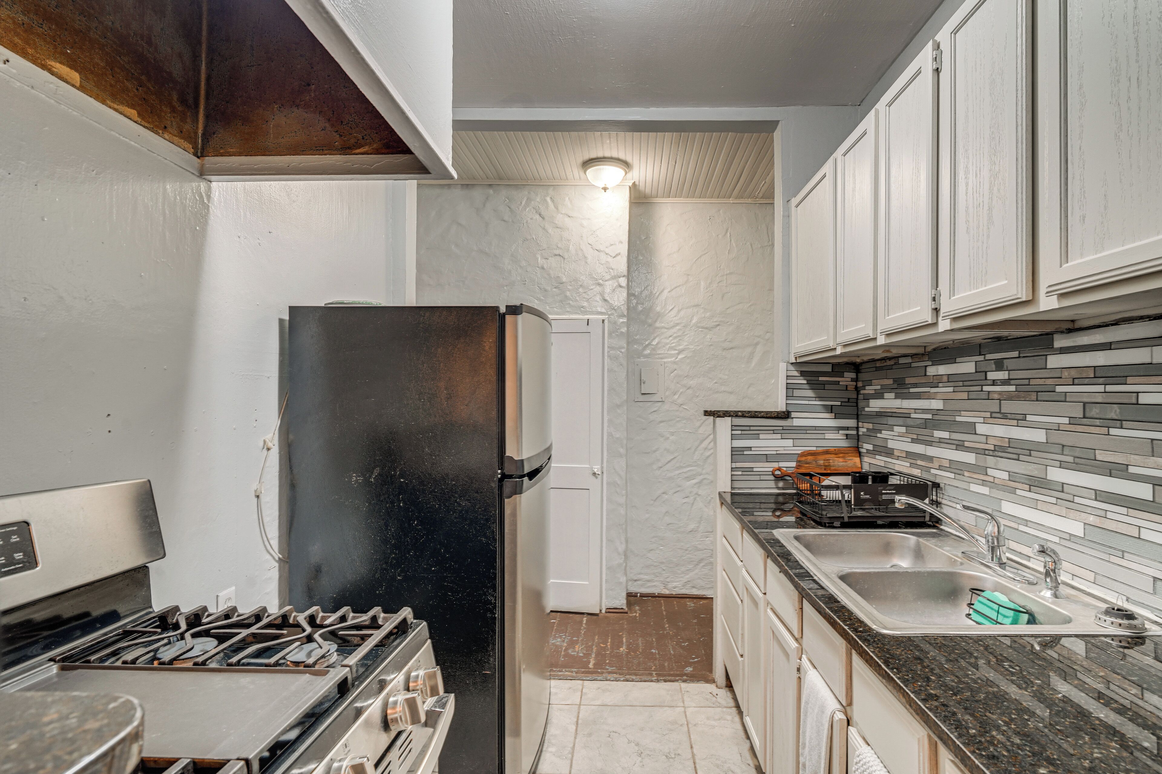 A compact kitchen with a black refrigerator, a stove, and a sink.