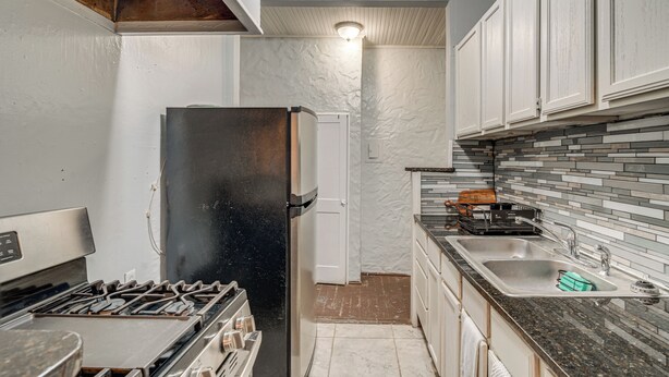 Una cocina compacta con un refrigerador negro, estufa y pileta.