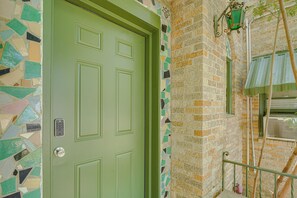A green door with a keypad lock, a mosaic-patterned wall, and a brick wall with a green awning. - Walk Everywhere! Monte Vista Apartment Near Cafes (San Antonio)