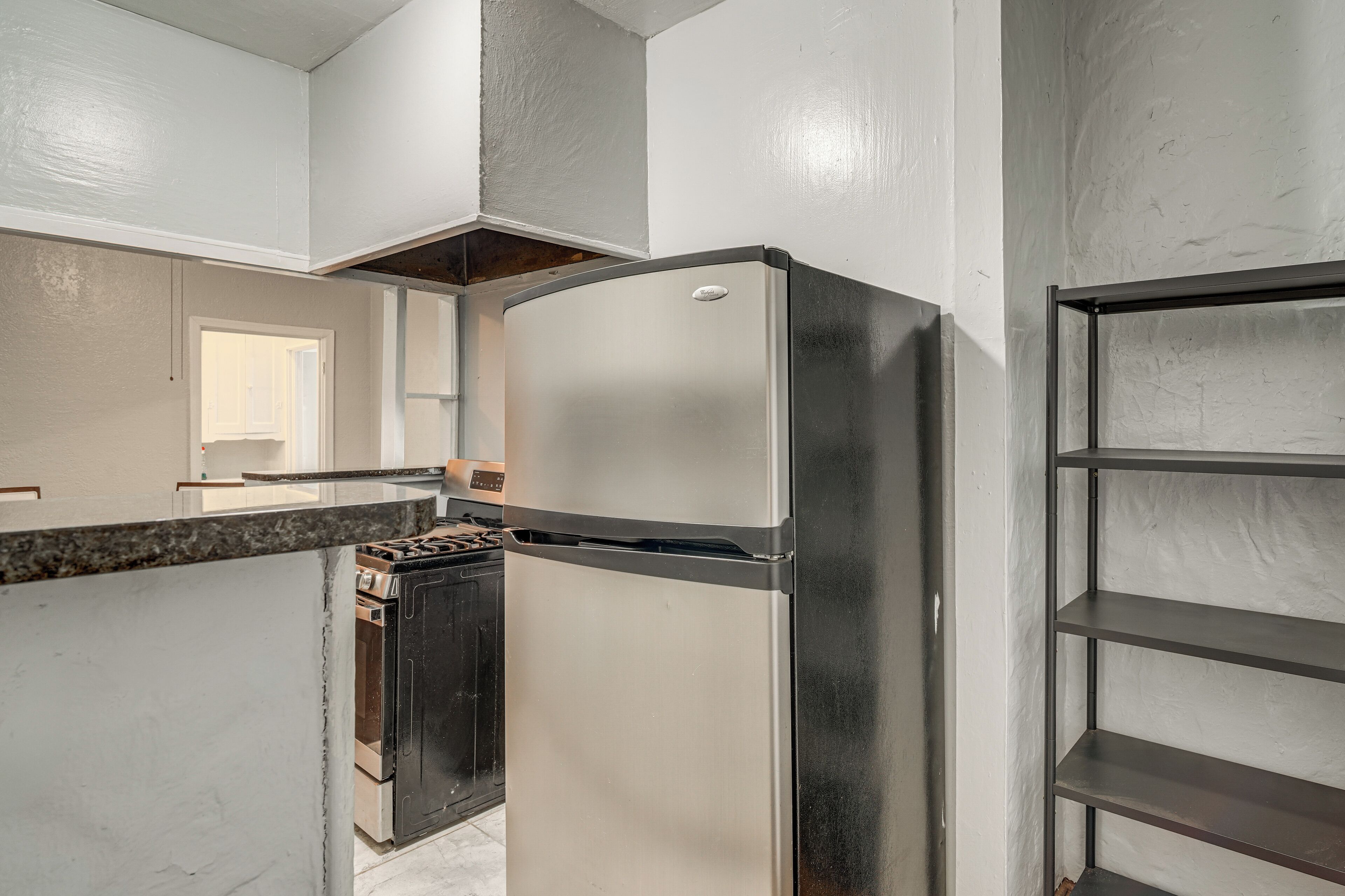 Una cocina con refrigerador de acero inoxidable, horno integrado y encimera de mármol.