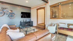 Ein modernes Wohnzimmer mit einer Ledersofa, einem an der Wand montierten Fernseher und einem Fahrrad, das an der Wand lehnt.