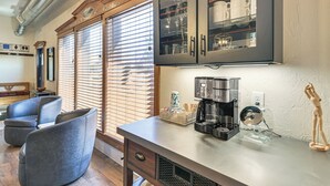 Eine moderne Küche mit integrierter Kaffeemaschine, einem Holzschrank mit Glastüren und einer Sitzecke mit Stühlen.