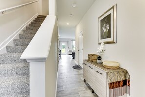 A hallway with a staircase, a white door, a framed picture, and a wooden cabinet with drawers. - Monthly Stay-Beautiful Townhouse-Luray Attractions (Luray)