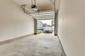 A garage with a car parked inside, a ceiling-mounted projector, and a clear view of the street outside. - Monthly Stay-Beautiful Townhouse-Luray Attractions (Luray)