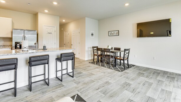 A modern kitchen with a central island, bar stools, a dining table with chairs, and a large mirror on the wall. - Monthly Stay-Beautiful Townhouse-Luray Attractions (Luray)