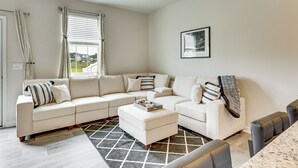 A modern living room with a sectional sofa, a coffee table, and a dining area with a marble countertop. - Monthly Stay-Beautiful Townhouse-Luray Attractions (Luray)
