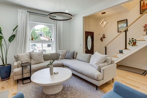 Ein Wohnzimmer mit Ecksofa, rundem Couchtisch und einer Treppe mit Geländer.