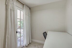 Ein Zimmer mit weißer Tür, einem weißen Stuhl und Blick auf eine Terrasse.