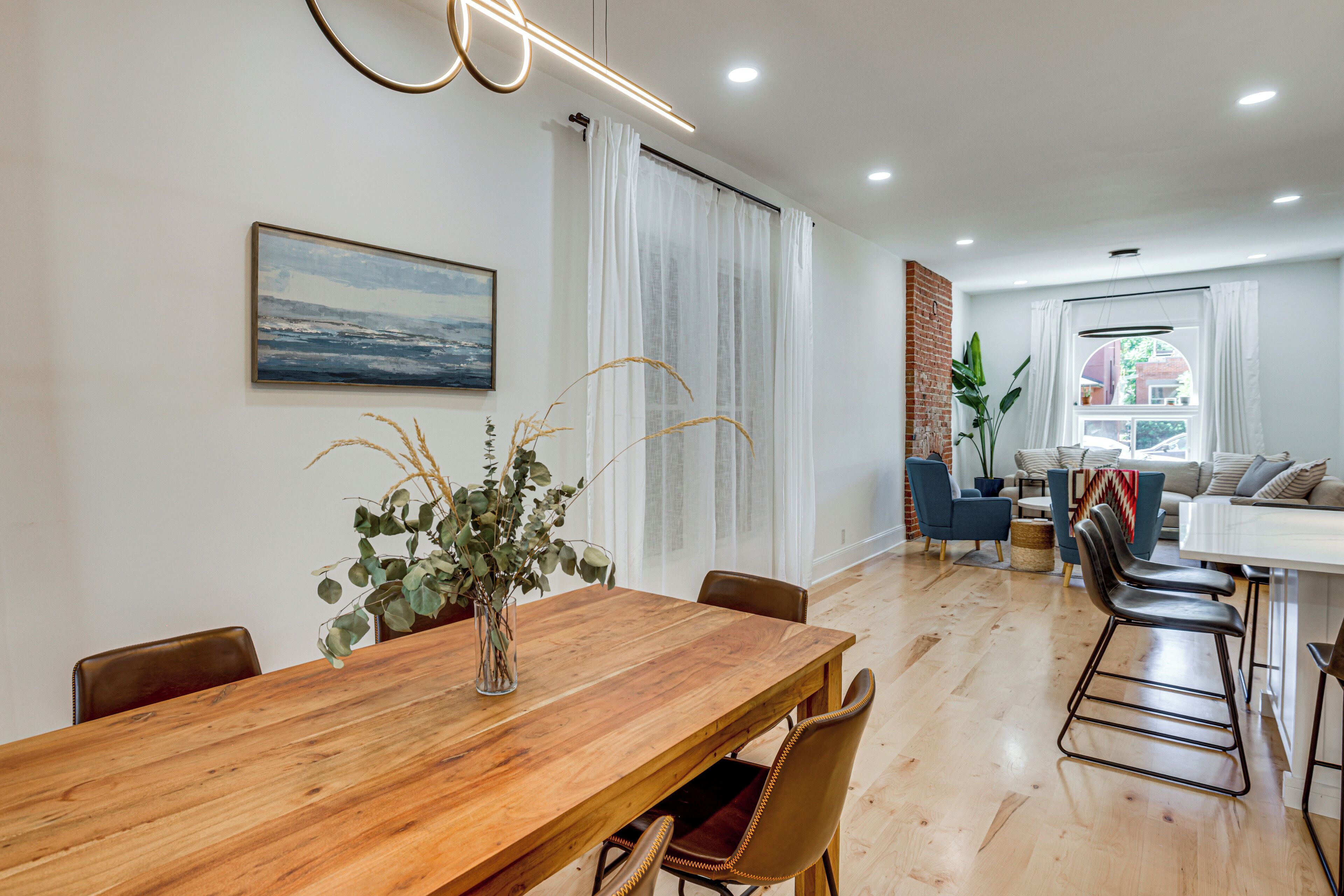 Un comedor moderno con una mesa de madera, sillas y un jarrón con plantas.