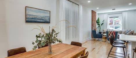 Un comedor moderno con una mesa de madera, sillas y un jarrón con plantas.