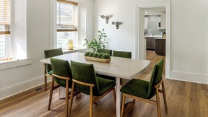 A dining area with a white table, green chairs, a plant centerpiece, and a kitchen in the background. - 4 Mi to Cedar Point! Spacious Home w/ Fenced Yard (Sandusky)