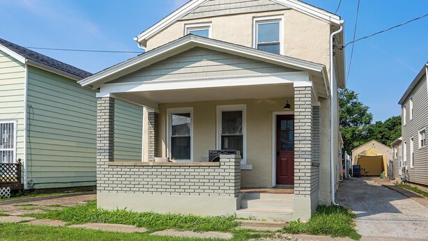A two-story residential house with a front porch, a brick column, and a red door. - 4 Mi to Cedar Point! Spacious Home w/ Fenced Yard (Sandusky)