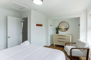 Ein Schlafzimmer mit Bett, Stuhl, Kommode und Spiegel.