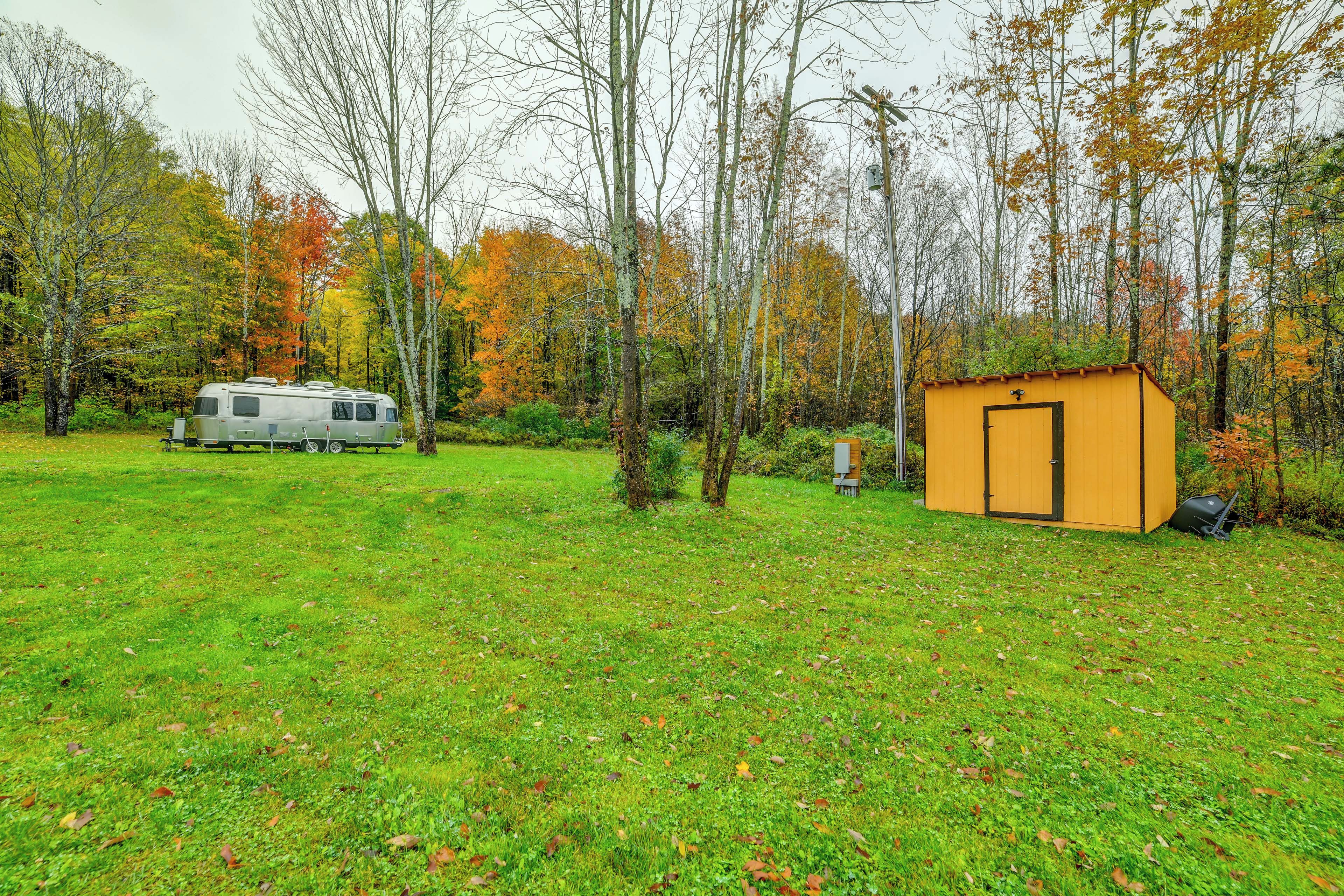 A campsite with a trailer and a small shed.